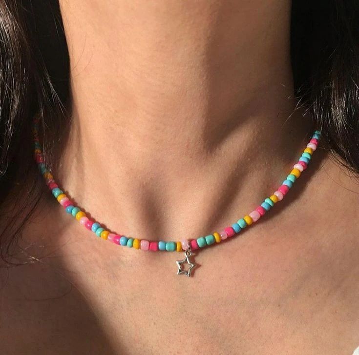 a woman wearing a multi colored beaded necklace with a silver star charm on it