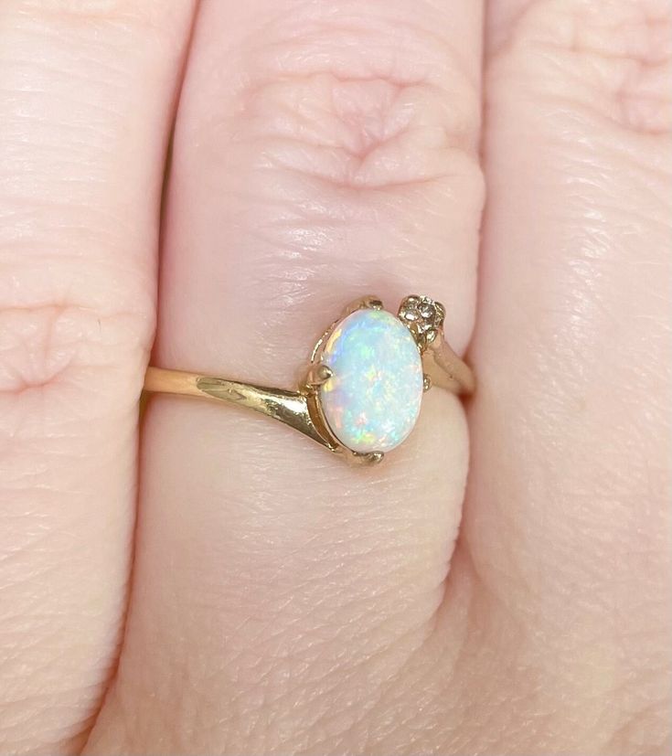 a woman's hand with a gold ring and an opal stone on it