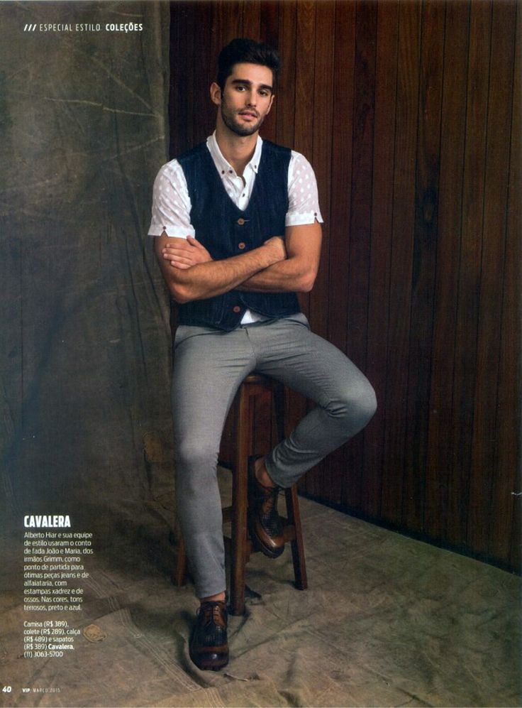 a man sitting on top of a wooden stool wearing grey pants and a white shirt