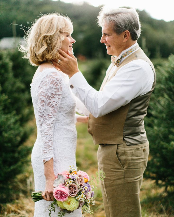 an older man and woman standing next to each other in front of christmas tree trees