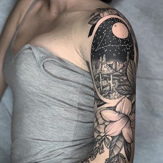 a woman with a tattoo on her arm is wearing a gray shirt and grey tank top