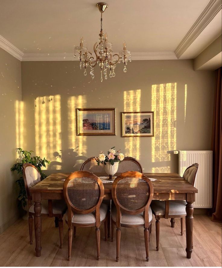 a dining room table with four chairs and a chandelier hanging from the ceiling