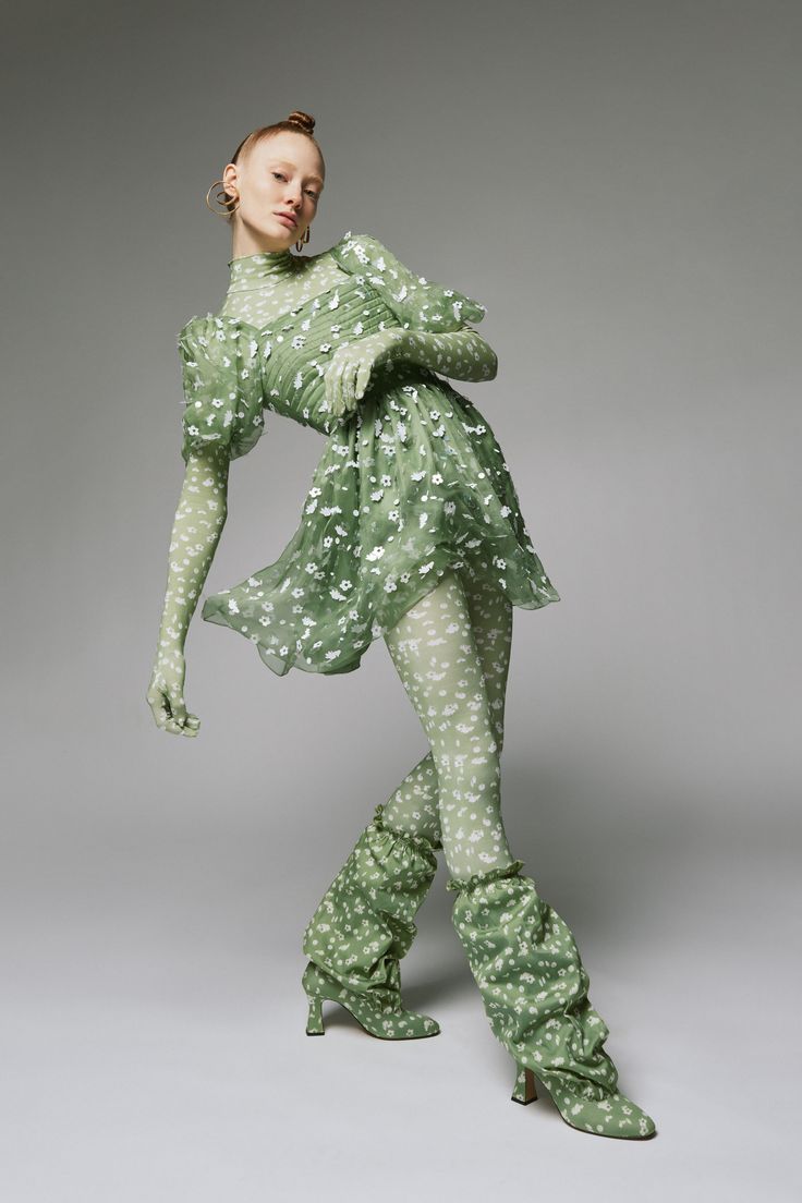 a woman is dressed in green and white polka dot print clothing, with her hands on her hips