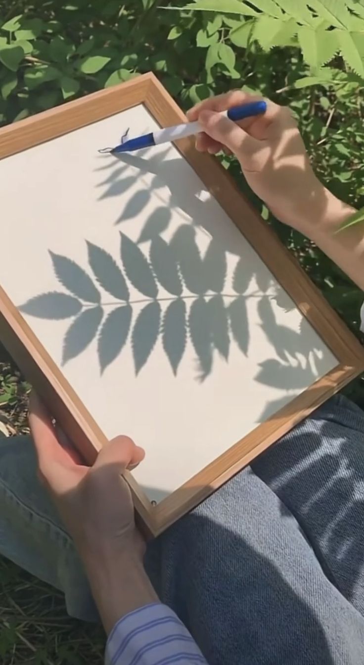 a person sitting in the grass drawing on a board