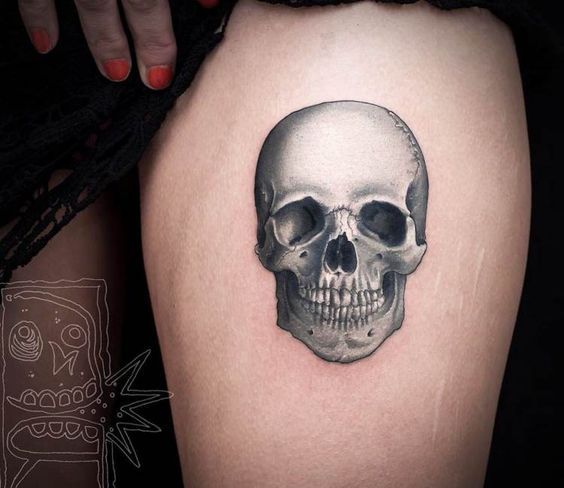 a woman's thigh with a skull tattoo on it