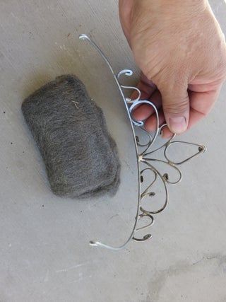 a hand is holding something next to a piece of wire and a cell phone holder