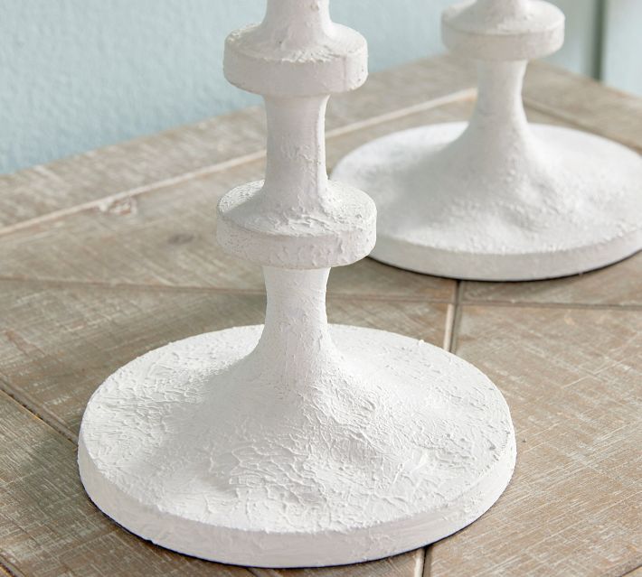 two white candlesticks sitting on top of a wooden table