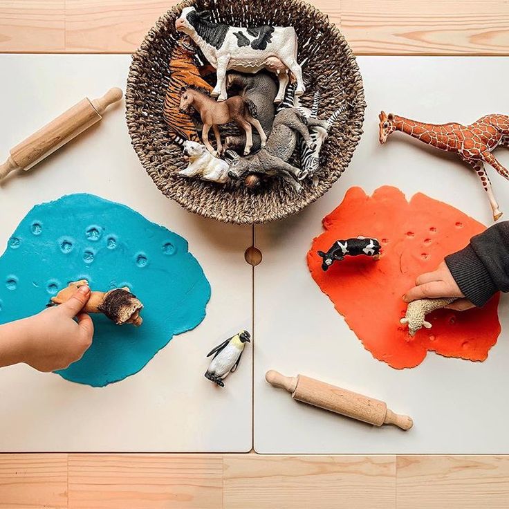 two children are playing with toys on the table together and making their own animal sculptures