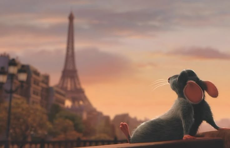 a small mouse sitting on top of a wooden fence next to the eiffel tower