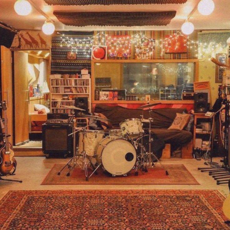 a living room filled with lots of musical instruments and lights hanging from the ceiling above