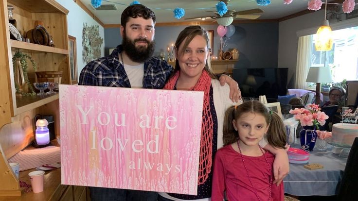 a man and two girls holding a sign that says you are loved in front of them