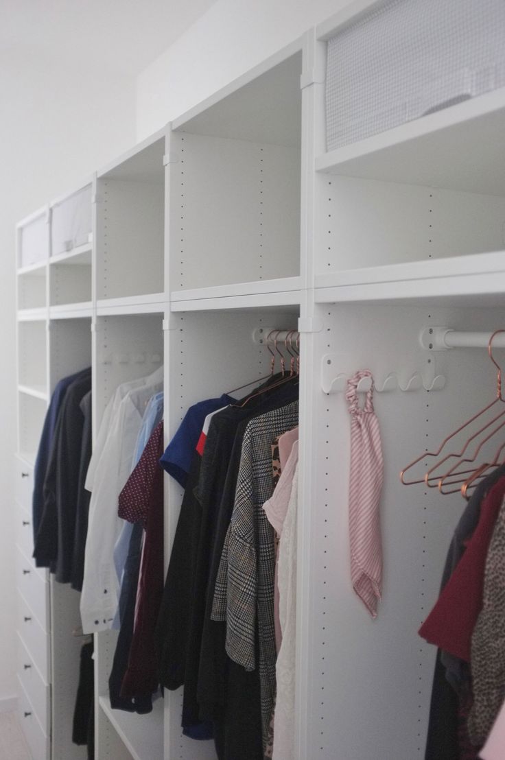 an organized closet with clothes hanging on the wall and several other items in front of it