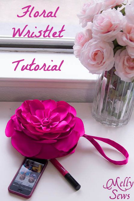 a pink flower sitting on top of a table next to a cell phone