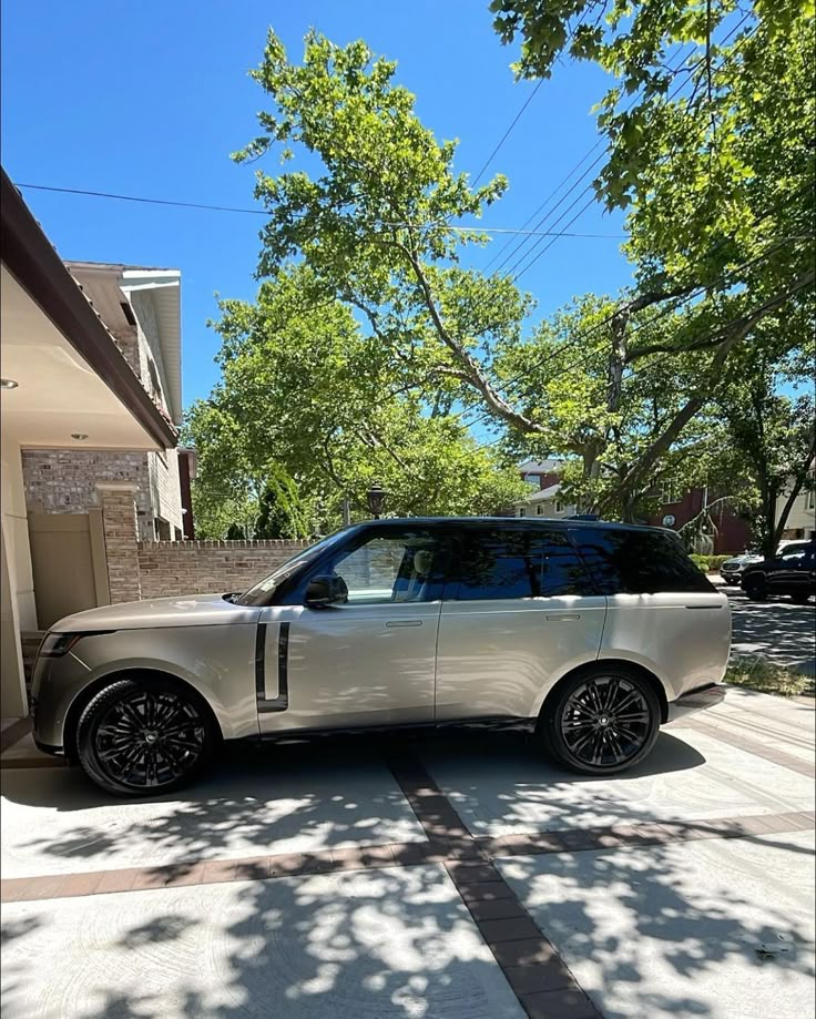 a white range rover parked in front of a house on a sunny day with trees