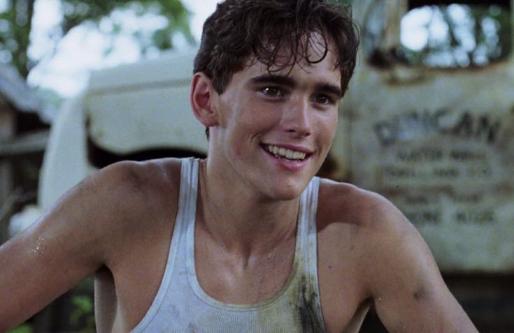 a young man in tank top smiling at the camera