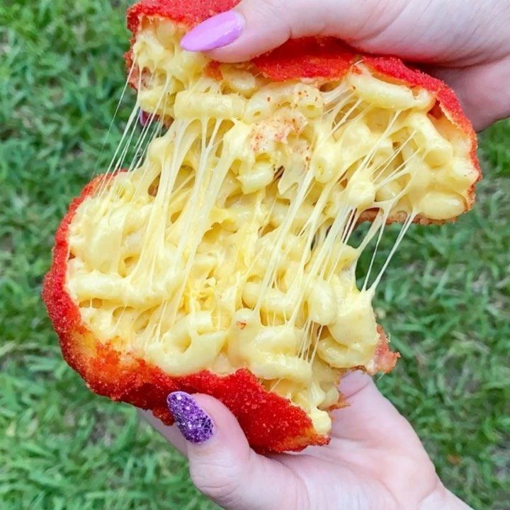 a person holding up a piece of food that looks like noodles and cheese on it