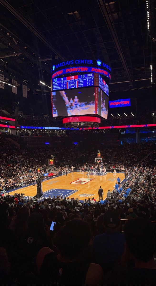 a basketball game is being played in an arena with people watching from the sidelines