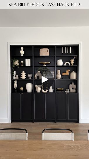 a bookcase filled with lots of vases on top of a wooden table