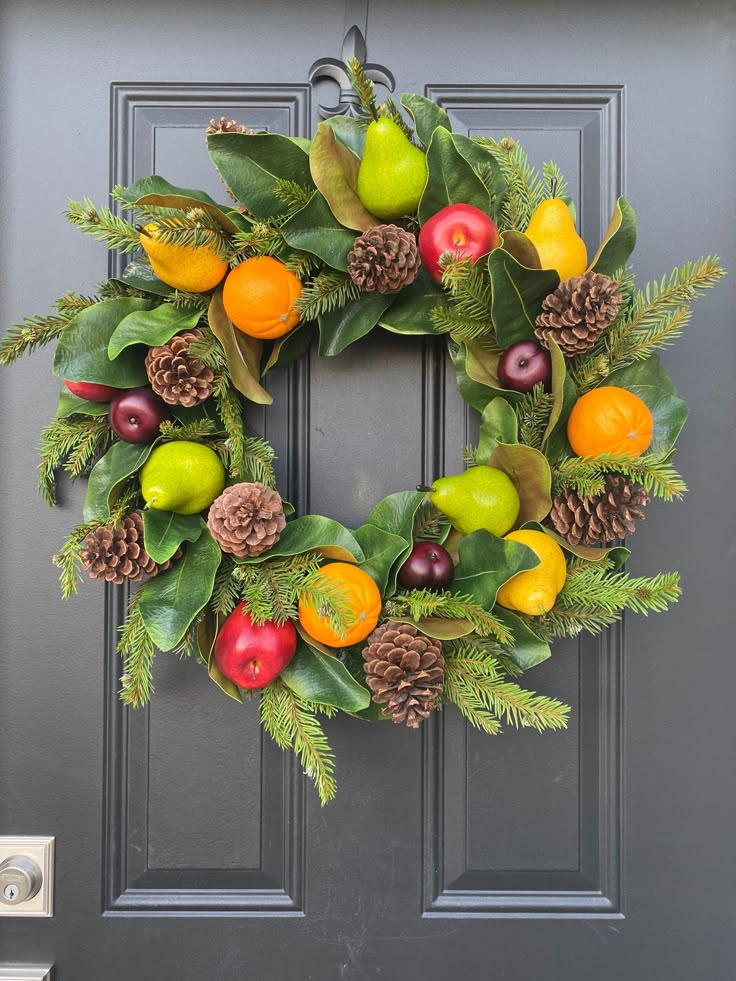 a wreath with fruit and pine cones on the front door