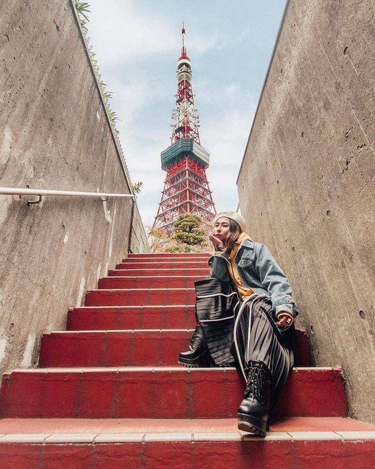 a man is sitting on the stairs in front of the eiffel tower