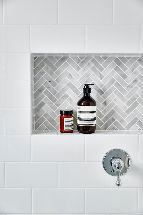 a white tiled bathroom with a red and black soap dispenser