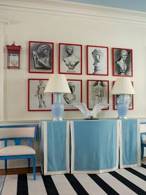 a living room with blue chairs and pictures on the wall above them, along with two lamps