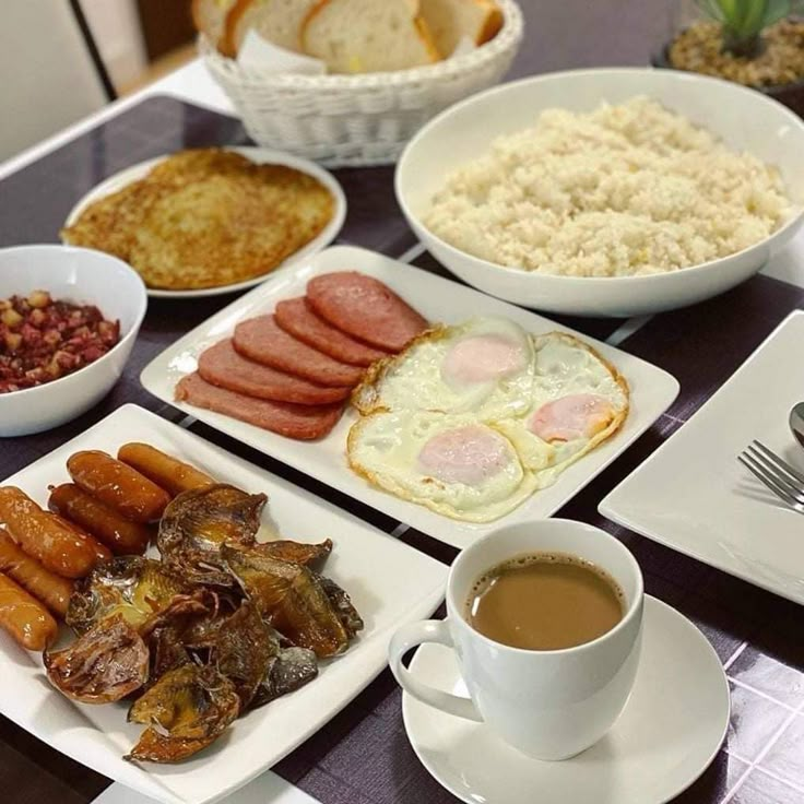 a table topped with plates of food and cups of coffee next to bowls of beans