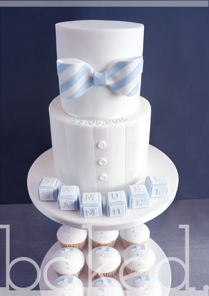 a white cake with blue and white bow ties on it's top is displayed