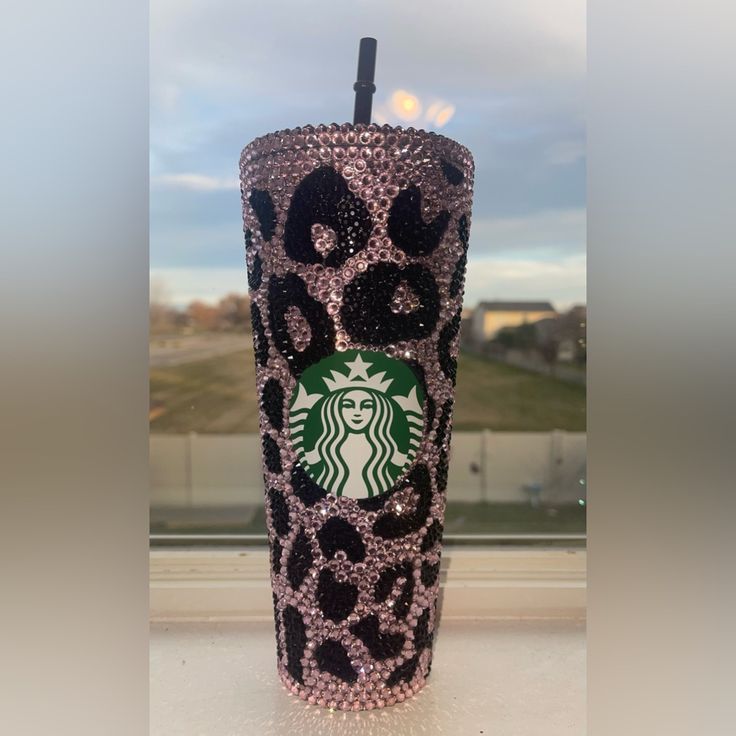 the starbucks cup is decorated with black and pink leopard print, which are accented with swaro dots