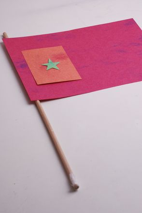 a pink piece of paper with a green star on it and a wooden stick sticking out of it