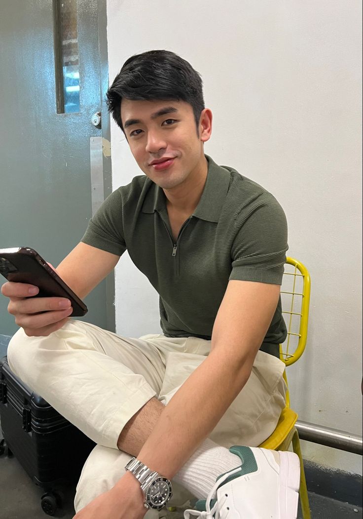 a man sitting on a yellow chair holding a cell phone and looking at the camera