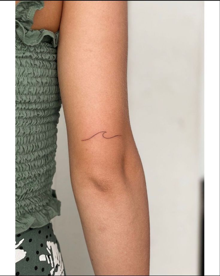 a woman's arm with a small wave tattoo on the left side of her arm