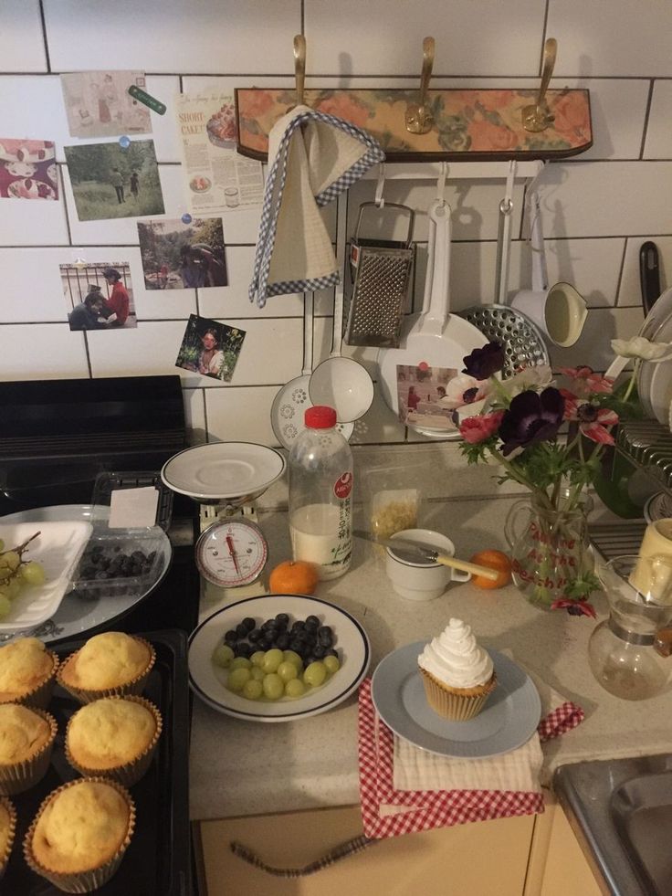 a kitchen counter with cupcakes, grapes and other food items on the counter