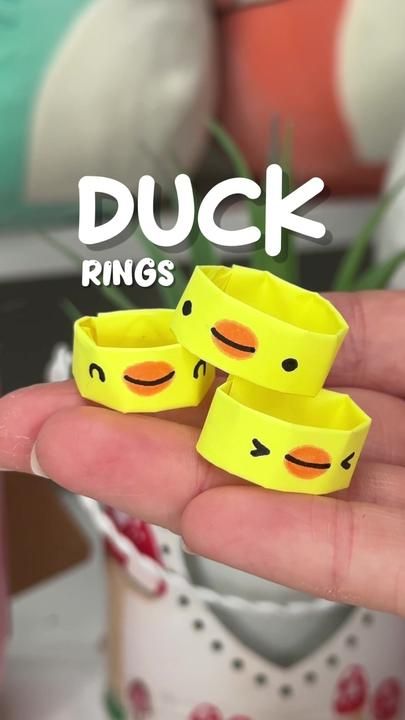 three yellow rubber rings with faces on them in the palm of someone's hand