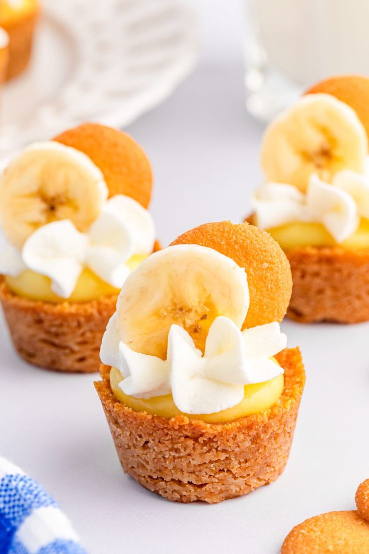 mini desserts with banana slices and whipped cream on them are sitting on a table