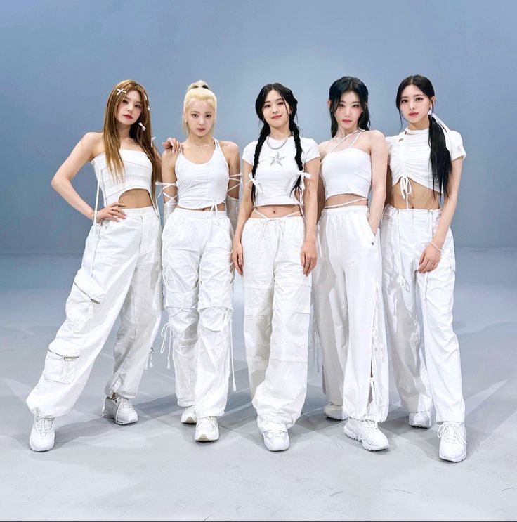 four women in white outfits posing for a photo with their hands on their hipss