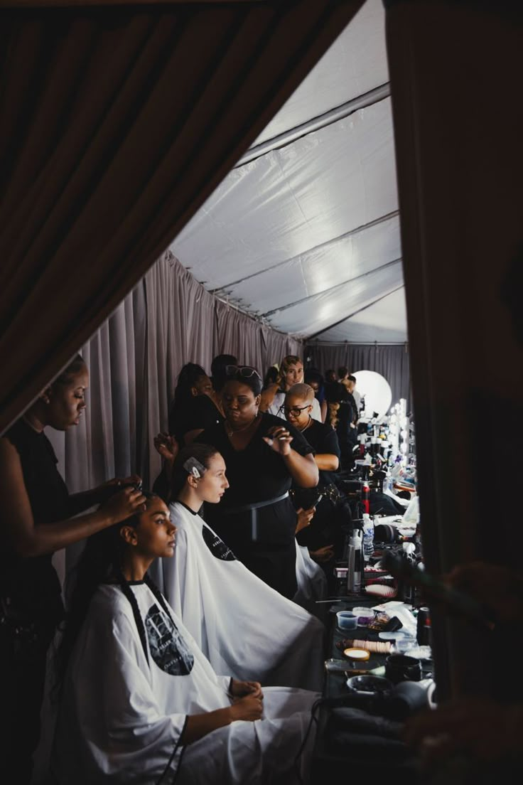 a group of people getting their hair done in a room with drapes on the walls