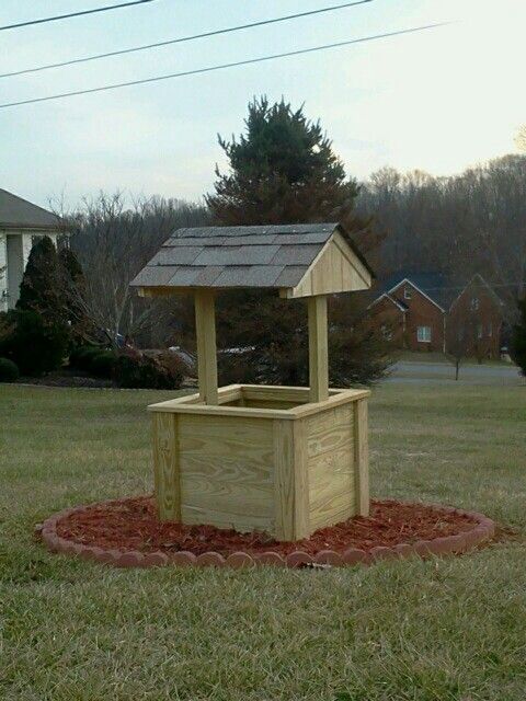 a wooden box with a roof on top in the grass