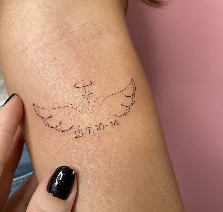 a woman's arm with a cross and angel tattoo on the left side of her arm