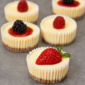 four small desserts with fruit on top and one has a speech bubble above it