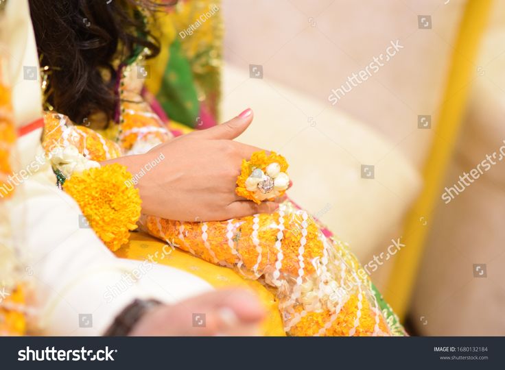 the bride is holding her wedding ring on her finger and wearing an elaborate yellow dress