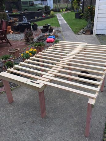 a wooden bed frame sitting in the middle of a yard