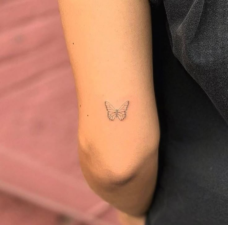 a woman's arm with a small butterfly tattoo on the back of her left arm