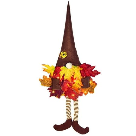 a scarecrow dressed in fall leaves and wearing a brown hat with flowers on it's head