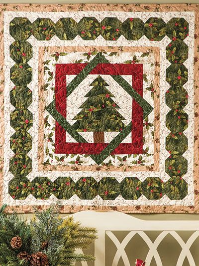 a christmas tree quilt hanging on the wall above a bench with potted plants in front of it