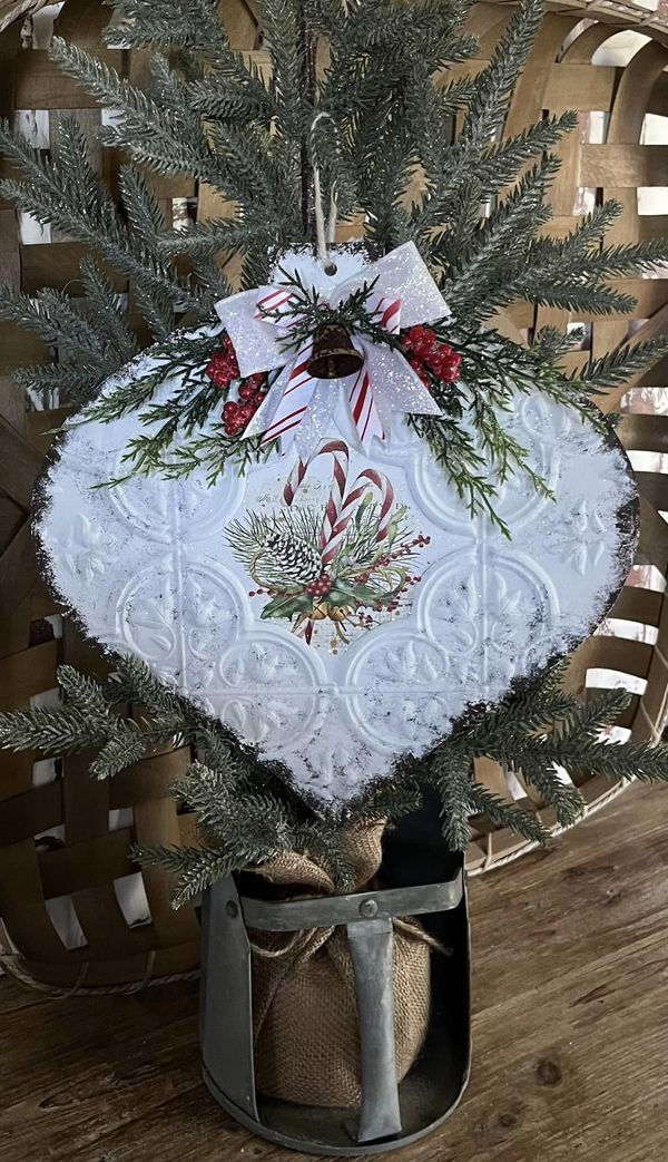 a white christmas ornament hanging from a tree in a basket on a wooden floor