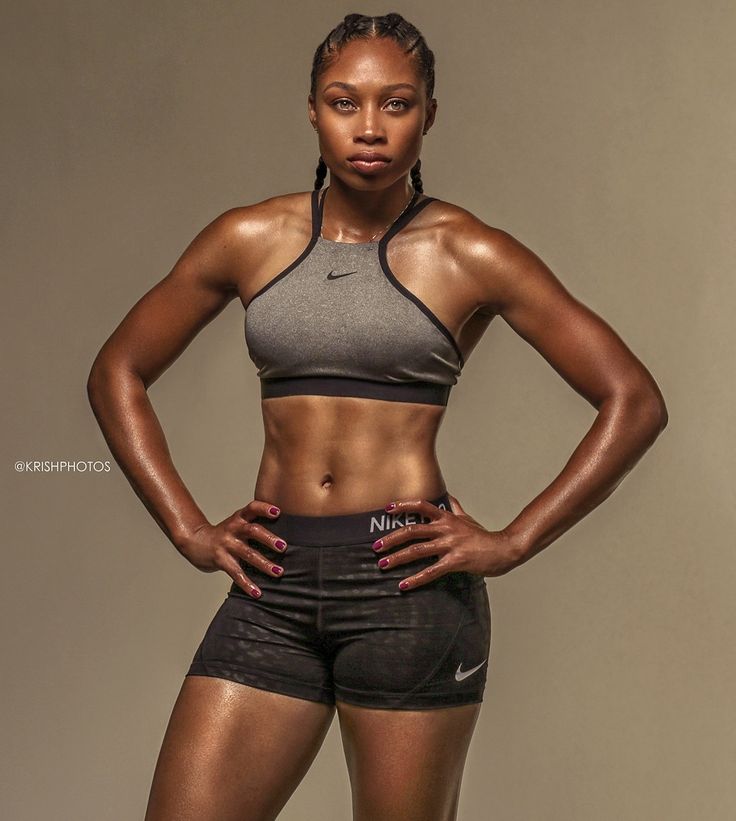 a woman with her hands on her hips posing for the camera while wearing black shorts and a sports bra top