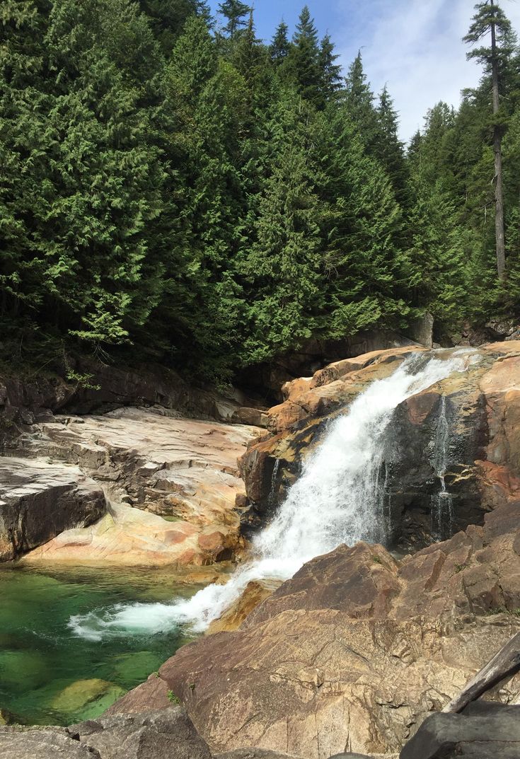 there is a small waterfall in the middle of some rocks and trees on the other side