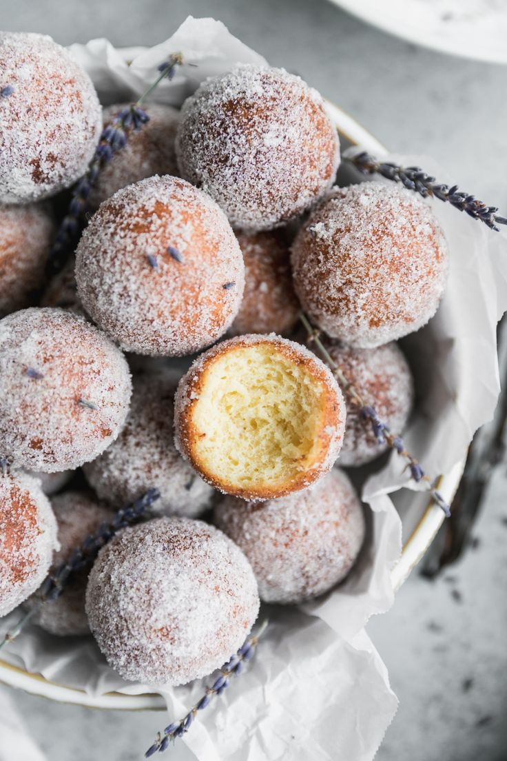 powdered sugar donuts in a bowl with lavender sprinkled on the side