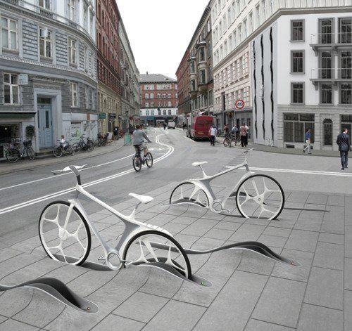 two bikes are parked on the sidewalk in front of some buildings and people walking down the street